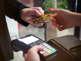 Pessoa pagando conta com cartão de crédito e uma máquina de cartão próxima simbolizando o tema Maquininha sem aluguel