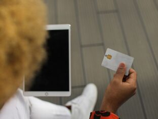 Rapaz segurando cartão de crédito com a mão direita para simbolizar o tema EMV