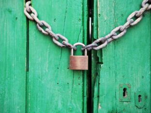 Foto de um cadeado com corrente trancando uma porta verde para simbolizar o tema Fechar uma empresa